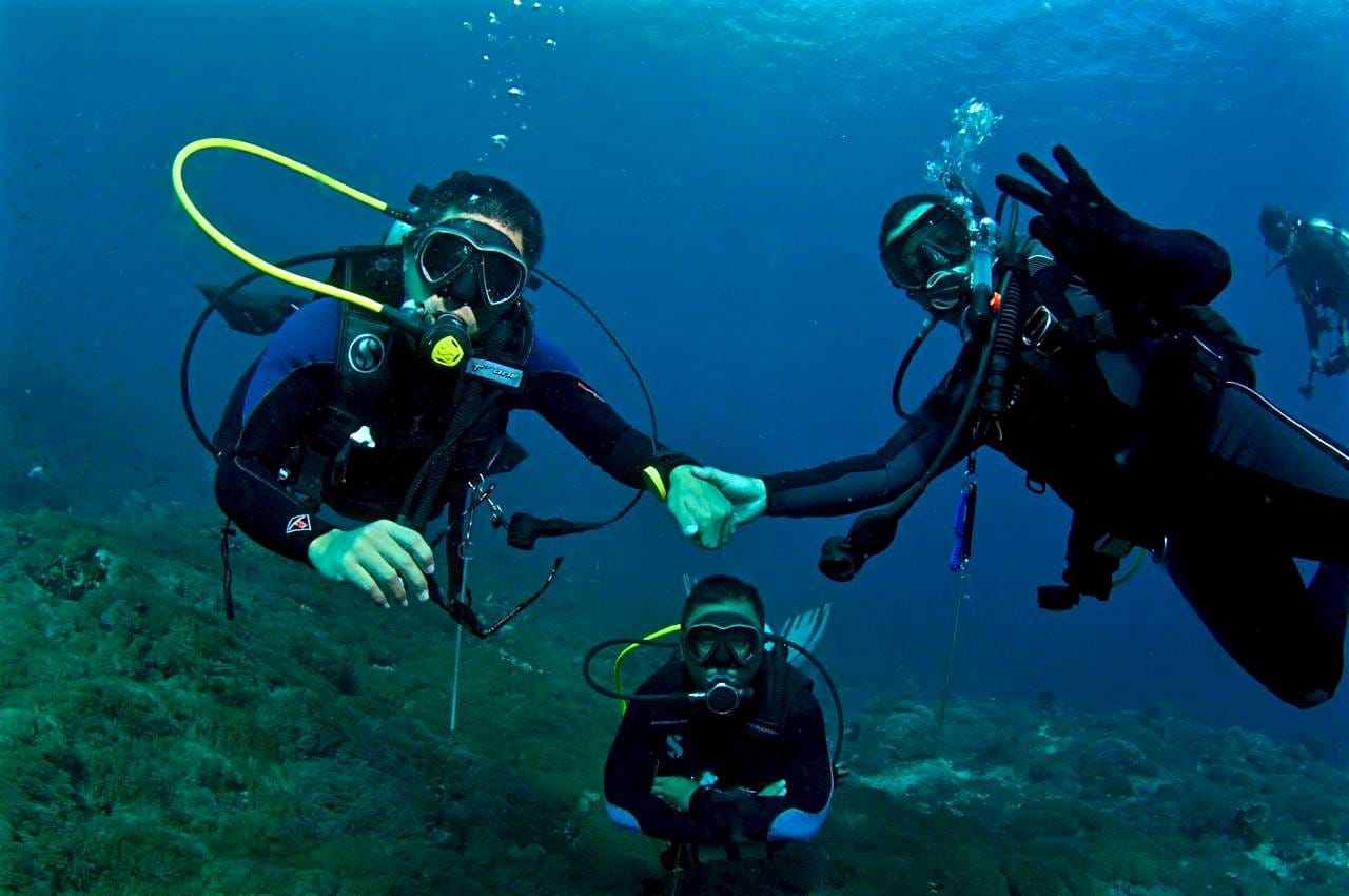 Scuba divers holding hands as a buddy team