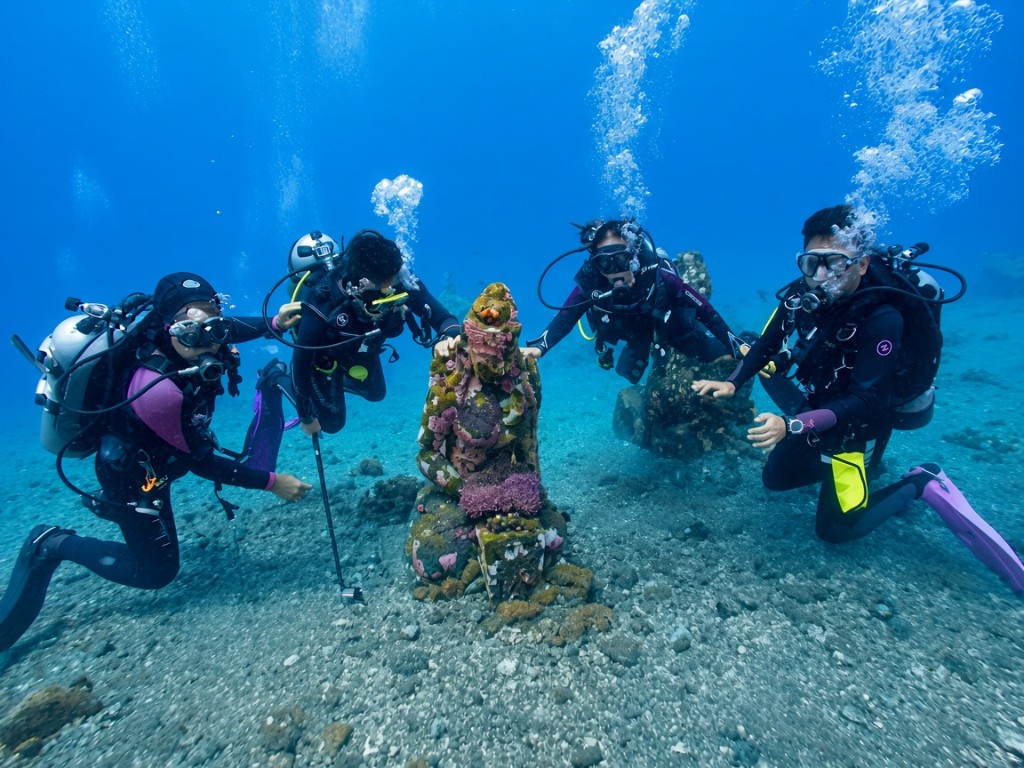 Divers exploring the underwater temple statues in Bali